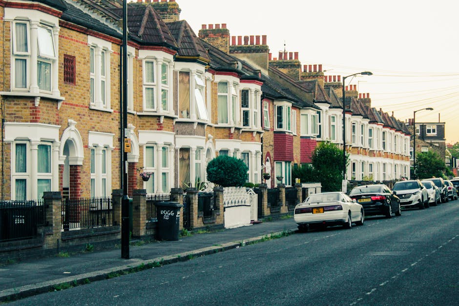 A street scene on Upper Tooting Road showing a row of multi-storey buildings with shops on the ground floor, including a café and retail outlets with signage, in a residential area under a partly clo